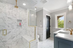 A bathroom with marble walls and floors, and a large shower.