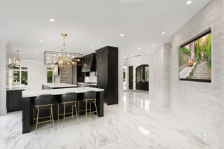A kitchen with marble floors and black cabinets.