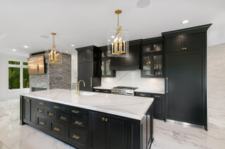 A kitchen with black cabinets and gold hardware.